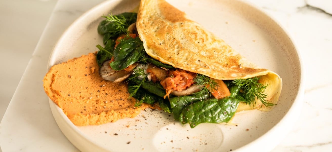 This is an image of a spinach and chicken omlette on a while plate.